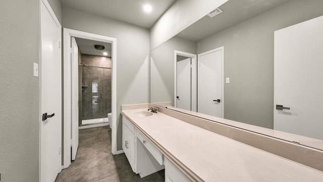 bathroom with tile patterned flooring, vanity, toilet, and tiled shower