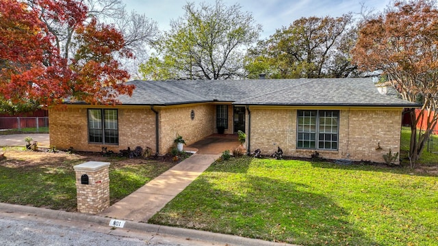 ranch-style home with a front yard, brick siding, and roof with shingles