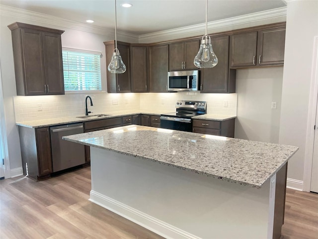 kitchen with sink, dark brown cabinets, appliances with stainless steel finishes, pendant lighting, and light stone countertops