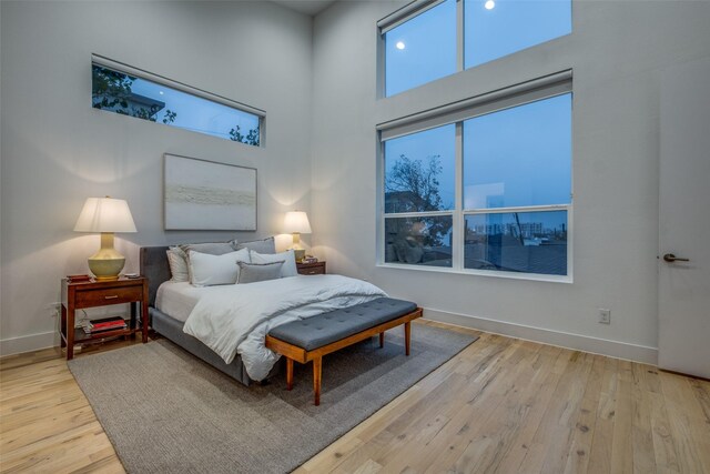 bedroom with a towering ceiling and light hardwood / wood-style flooring