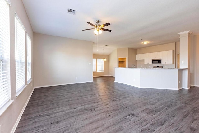 unfurnished living room with ceiling fan with notable chandelier and dark hardwood / wood-style floors