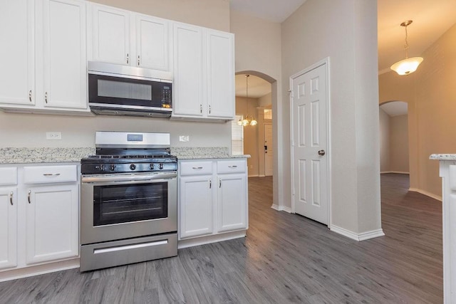 kitchen featuring white cabinets, decorative light fixtures, hardwood / wood-style flooring, and appliances with stainless steel finishes