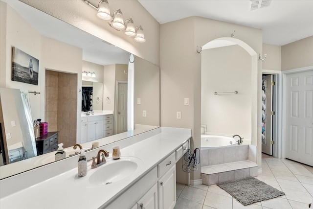 bathroom with tile patterned floors, tiled tub, and vanity