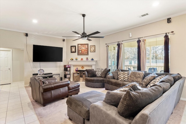 living room with ceiling fan, light tile patterned flooring, ornamental molding, and a fireplace