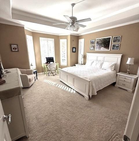 bedroom with carpet, a tray ceiling, ceiling fan, and ornamental molding