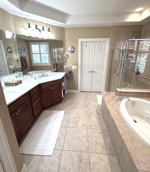 bathroom with vanity, a tray ceiling, shower with separate bathtub, and tile patterned flooring