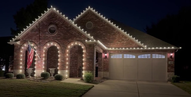 view of front of property featuring a garage, brick siding, and driveway