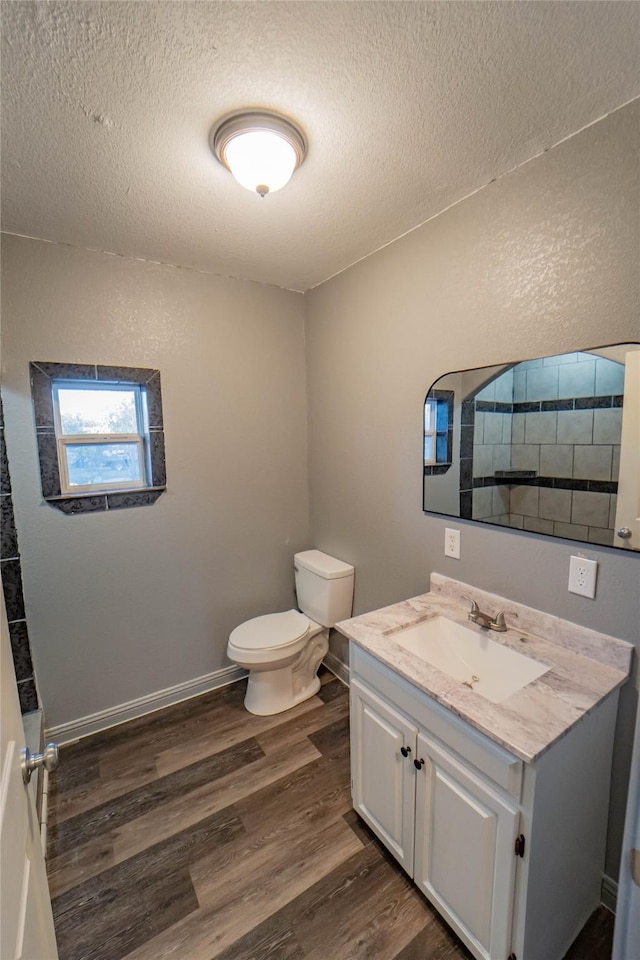 bathroom featuring wood-type flooring, toilet, a textured ceiling, and vanity