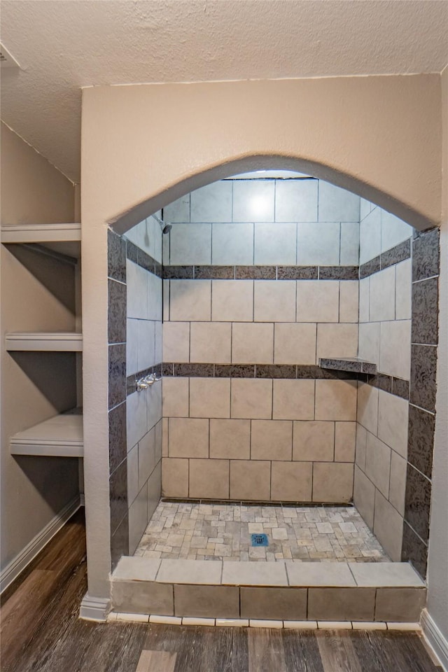 bathroom with hardwood / wood-style flooring, a textured ceiling, and tiled shower