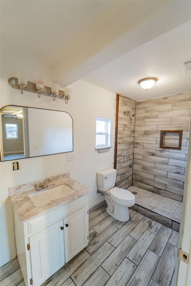 bathroom featuring vanity, toilet, and a tile shower