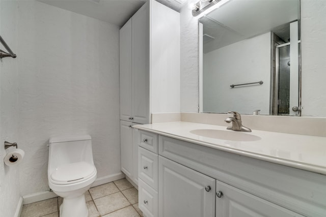 bathroom with tile patterned flooring, vanity, toilet, and walk in shower