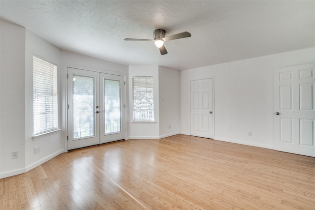 empty room with light hardwood / wood-style floors, a textured ceiling, ceiling fan, and french doors