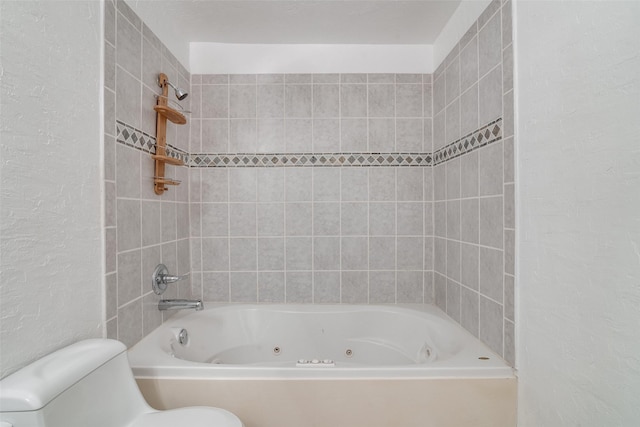 bathroom featuring tiled shower / bath and toilet