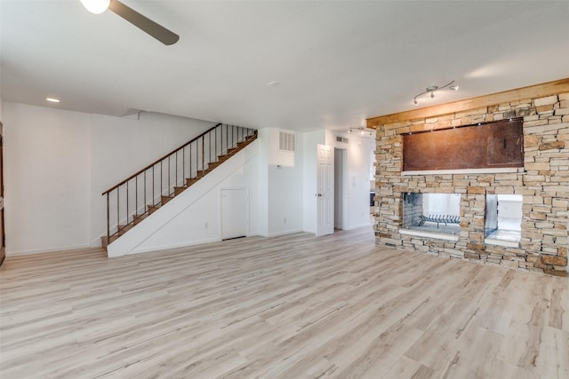 unfurnished living room featuring a stone fireplace and light wood-type flooring