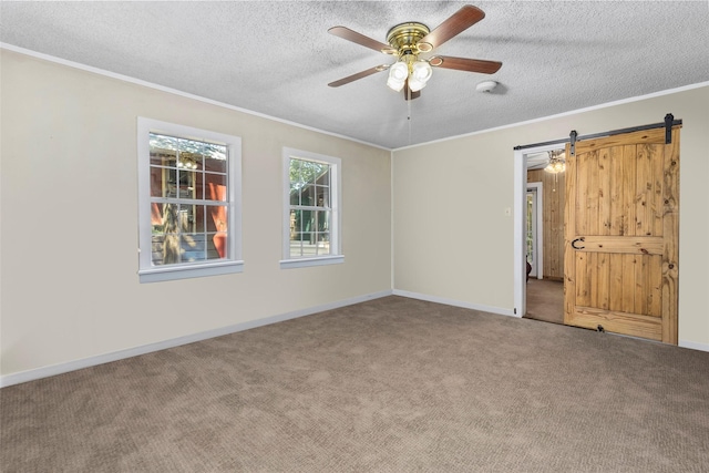 interior space featuring crown molding, ceiling fan, carpet, a textured ceiling, and a barn door