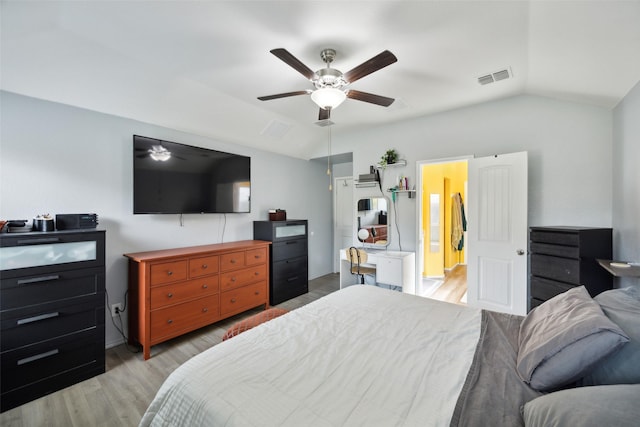 bedroom featuring ceiling fan, light hardwood / wood-style floors, ensuite bath, and vaulted ceiling