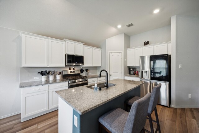 kitchen featuring appliances with stainless steel finishes, a kitchen island with sink, sink, hardwood / wood-style flooring, and white cabinets