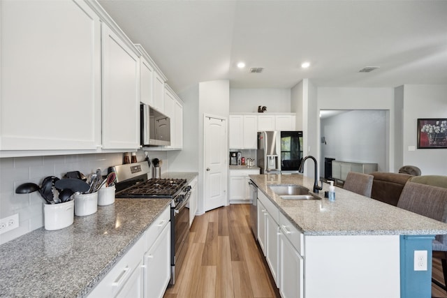 kitchen featuring appliances with stainless steel finishes, sink, a center island with sink, white cabinetry, and a breakfast bar area