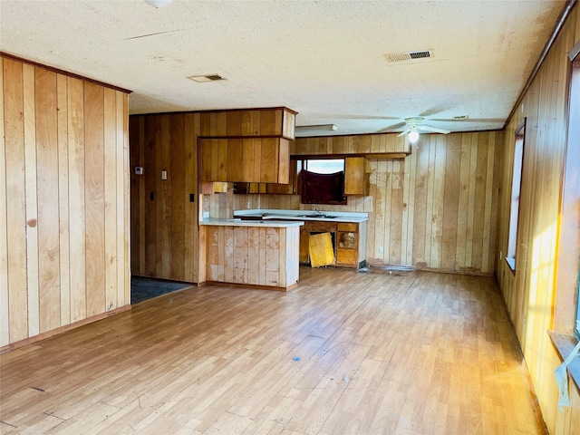 kitchen with kitchen peninsula, light wood-type flooring, and wooden walls