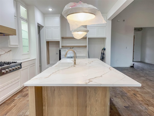 kitchen with white cabinets, a kitchen island, light stone counters, and sink