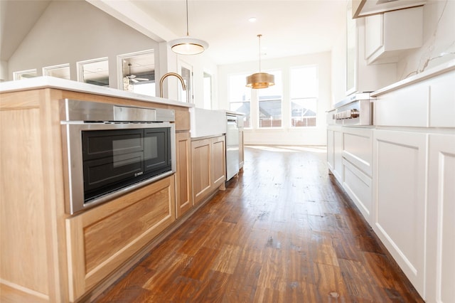 kitchen featuring decorative light fixtures, white cabinetry, stainless steel dishwasher, dark wood-type flooring, and light brown cabinets