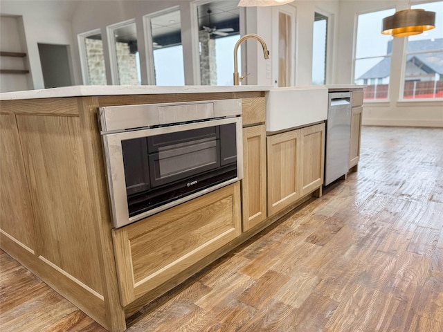 kitchen with ceiling fan, light brown cabinets, oven, and light hardwood / wood-style floors