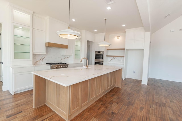 kitchen featuring double oven, white cabinets, hanging light fixtures, a large island, and light stone countertops