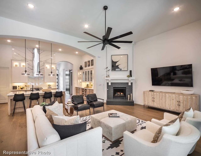4121 Buffalo Clover Dr, Aubrey, TX 76227 - living area with wood finished floors, ceiling fan, arched walkways, recessed lighting, and a fireplace