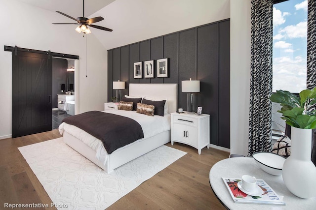 4121 Buffalo Clover Dr, Aubrey, TX 76227 - bedroom with a barn door, light wood-type flooring, connected bathroom, high vaulted ceiling, and ceiling fan