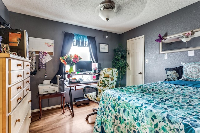 bedroom with a textured ceiling, hardwood / wood-style flooring, and ceiling fan