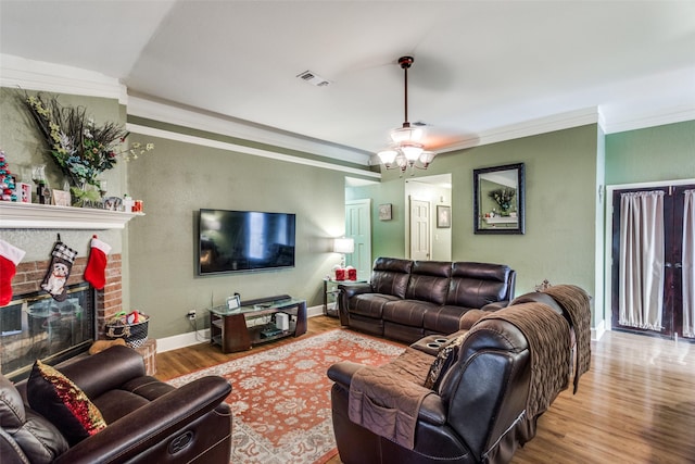 living room featuring a fireplace, ornamental molding, and hardwood / wood-style flooring