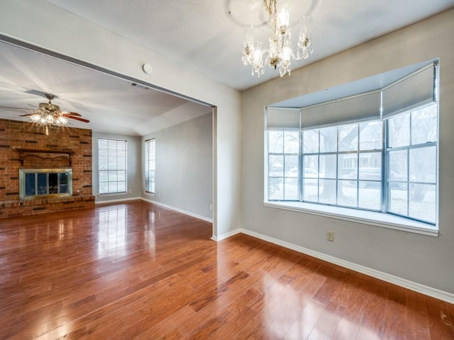 unfurnished living room featuring hardwood / wood-style floors, ceiling fan with notable chandelier, and a fireplace