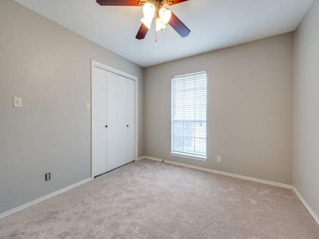 unfurnished bedroom featuring light colored carpet, ceiling fan, and a closet