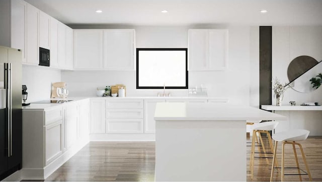 kitchen with black microwave, sink, white cabinets, and light wood-type flooring