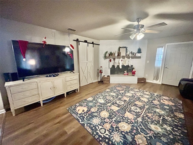 living room featuring dark hardwood / wood-style flooring, a barn door, a textured ceiling, and ceiling fan