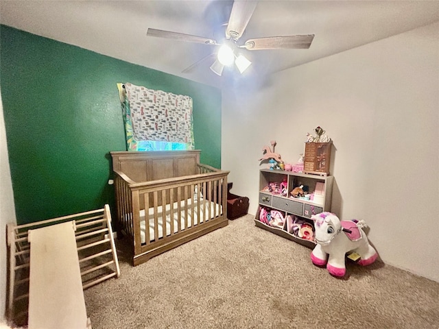 carpeted bedroom with ceiling fan and a nursery area