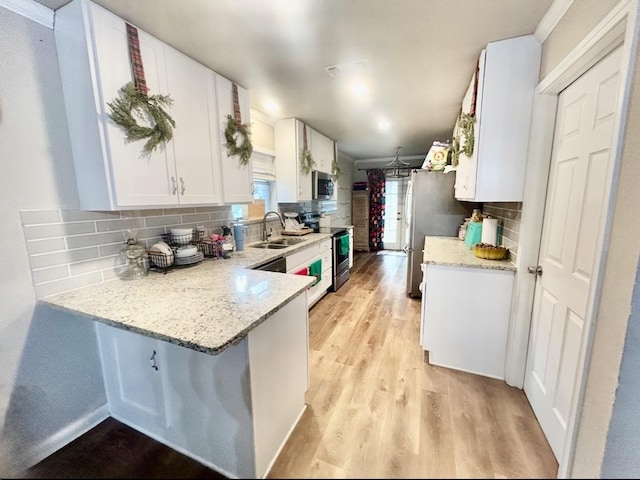 kitchen with white cabinetry, light stone countertops, stainless steel appliances, and sink