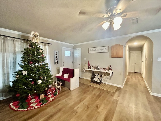 interior space featuring a textured ceiling, light hardwood / wood-style floors, ceiling fan, and crown molding