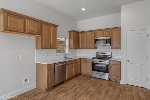 kitchen featuring decorative backsplash, appliances with stainless steel finishes, hardwood / wood-style flooring, and sink