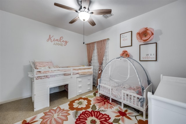 bedroom featuring ceiling fan, a crib, and light carpet