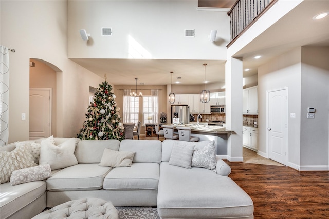 living room featuring hardwood / wood-style floors, a towering ceiling, sink, and an inviting chandelier