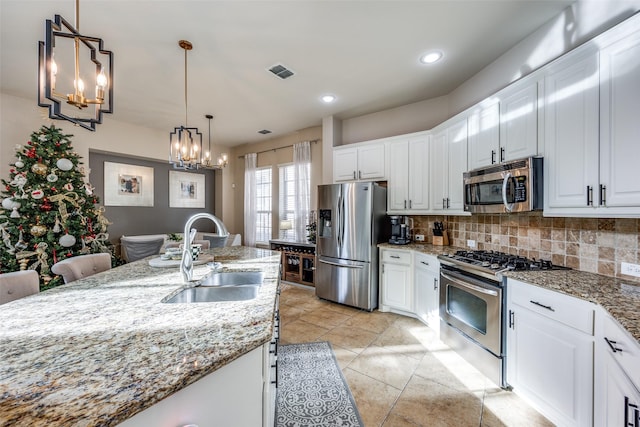 kitchen with white cabinets, sink, light stone countertops, and stainless steel appliances