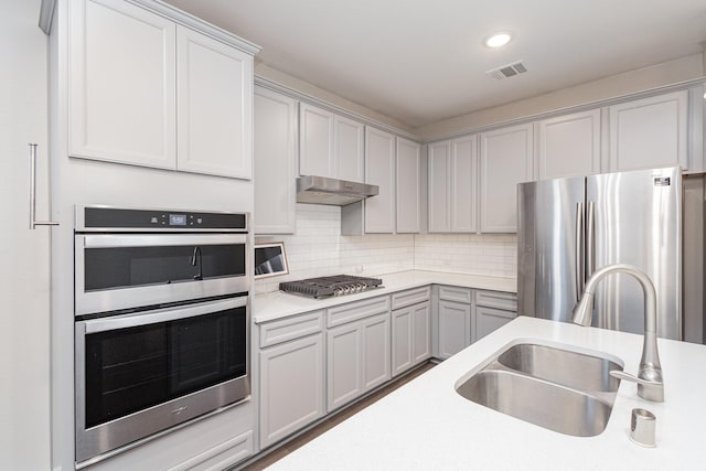 kitchen featuring backsplash, gray cabinetry, sink, and appliances with stainless steel finishes