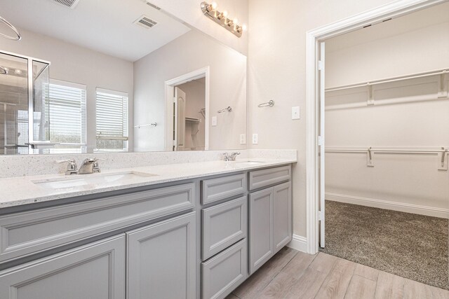 2013 Barx Dr, Little Elm, TX 75068 - bathroom featuring double vanity, a spacious closet, wood finished floors, and a tile shower