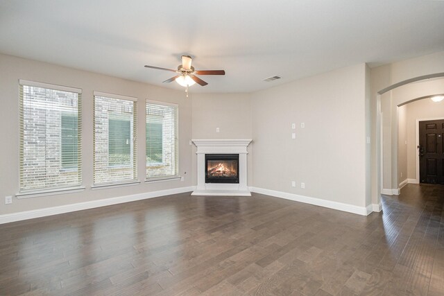 2013 Barx Dr, Little Elm, TX 75068 - unfurnished living room featuring arched walkways, a ceiling fan, dark wood finished floors, and a glass covered fireplace