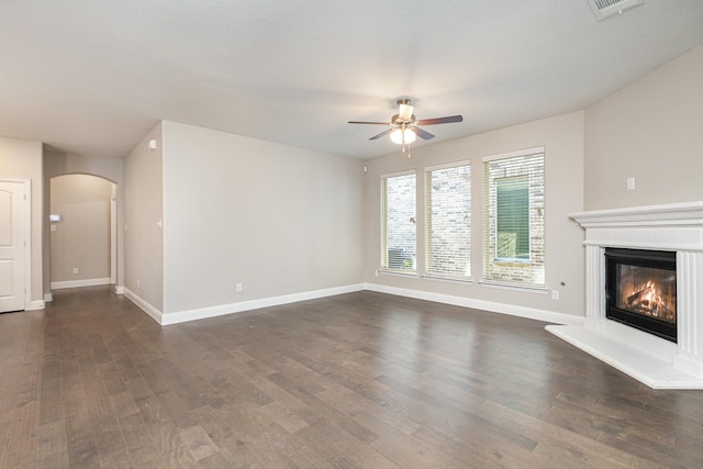 2013 Barx Dr, Little Elm, TX 75068 - unfurnished living room featuring a ceiling fan, dark wood finished floors, arched walkways, and a glass covered fireplace