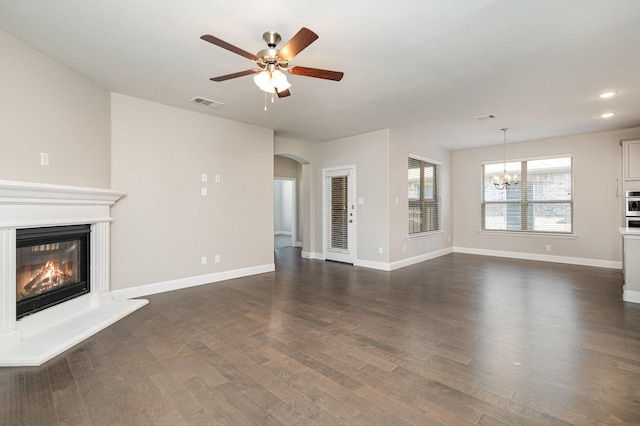 unfurnished living room with ceiling fan with notable chandelier and dark hardwood / wood-style flooring