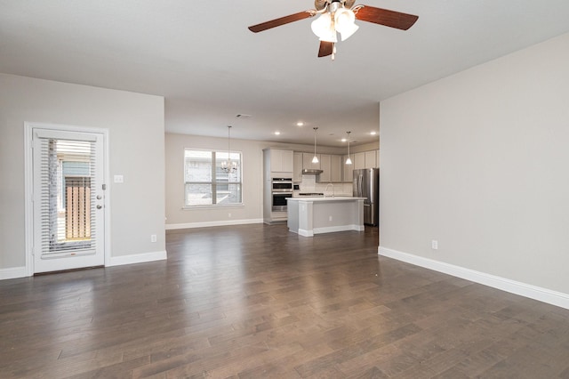 unfurnished living room featuring ceiling fan, dark hardwood / wood-style flooring, and sink