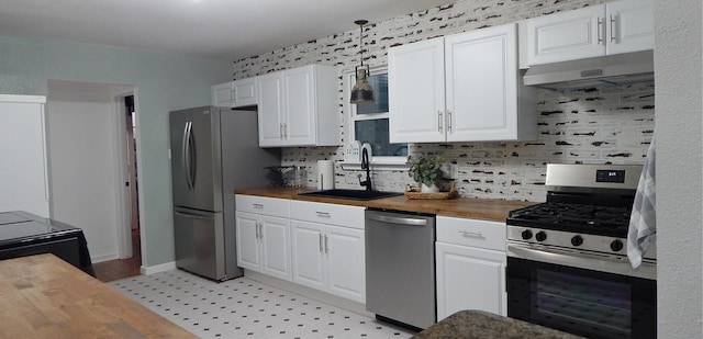 kitchen with appliances with stainless steel finishes, butcher block countertops, white cabinetry, and sink