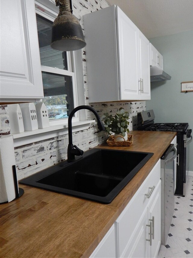 kitchen featuring white cabinets, wood counters, sink, and appliances with stainless steel finishes